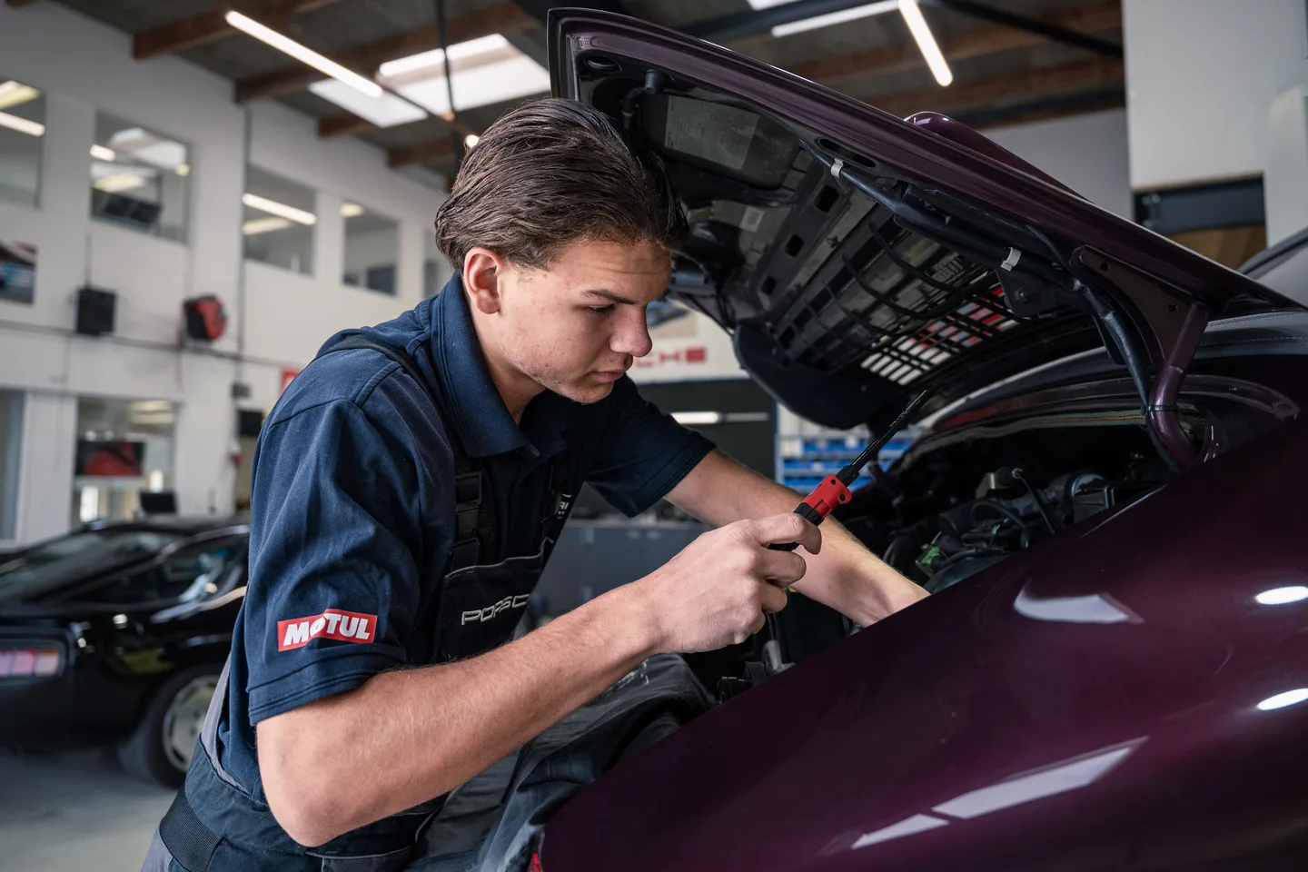 GTAX Repair mechanic working beneath an open bonnet