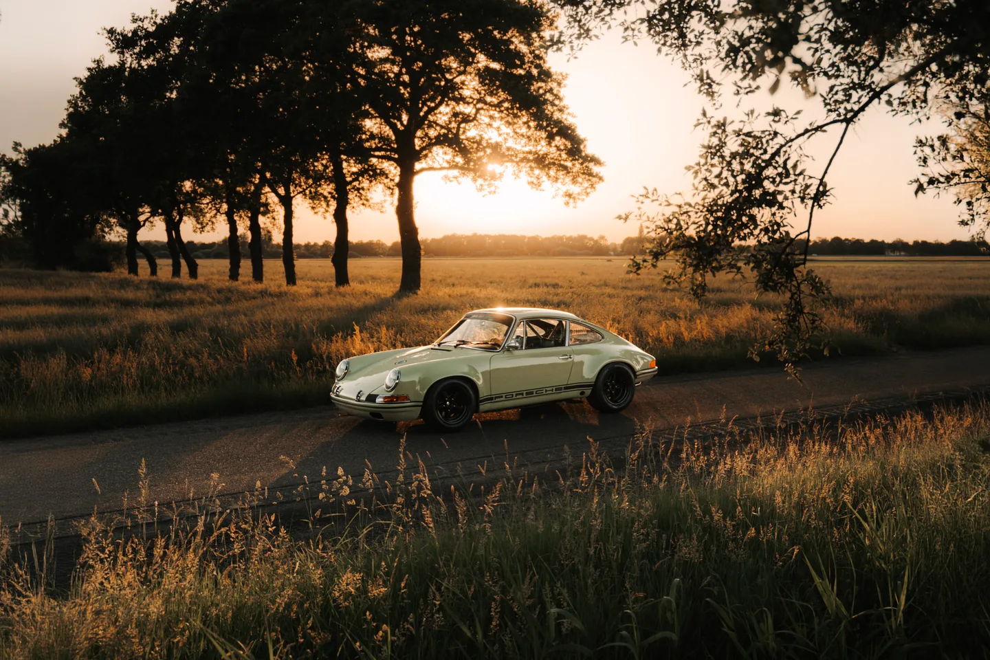 Classic sports car in a field at sunset