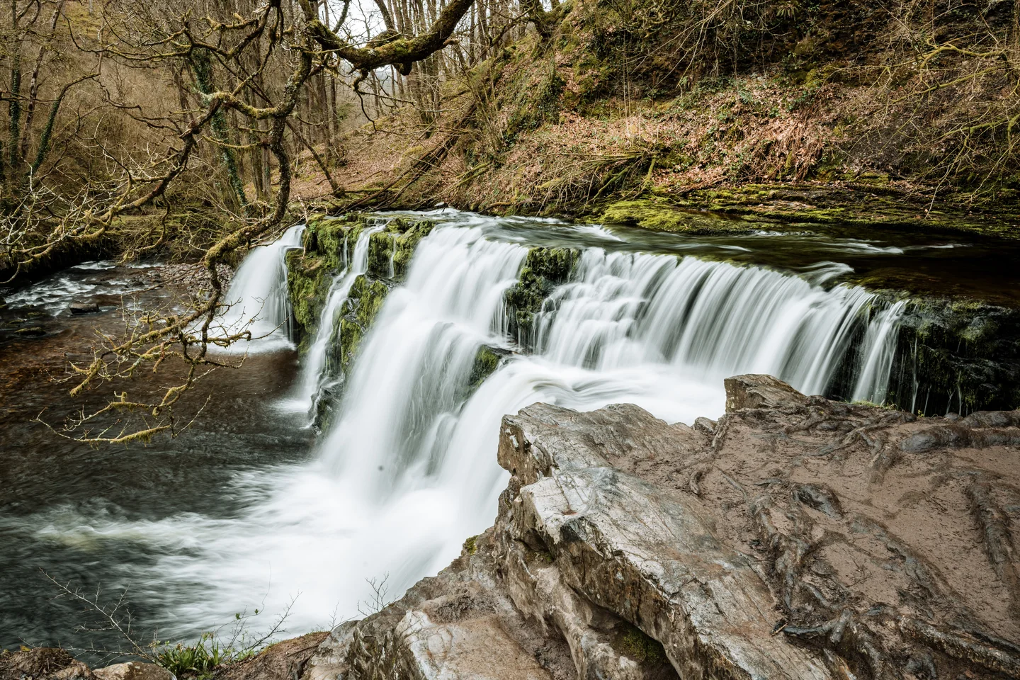 Wide waterfall running between rocks and trees