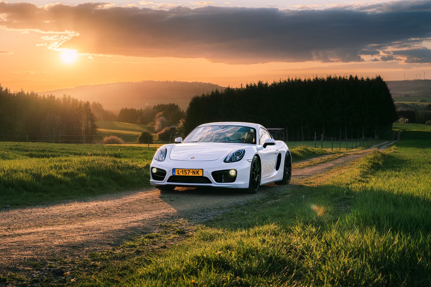 White Porsche on a country road at sunset