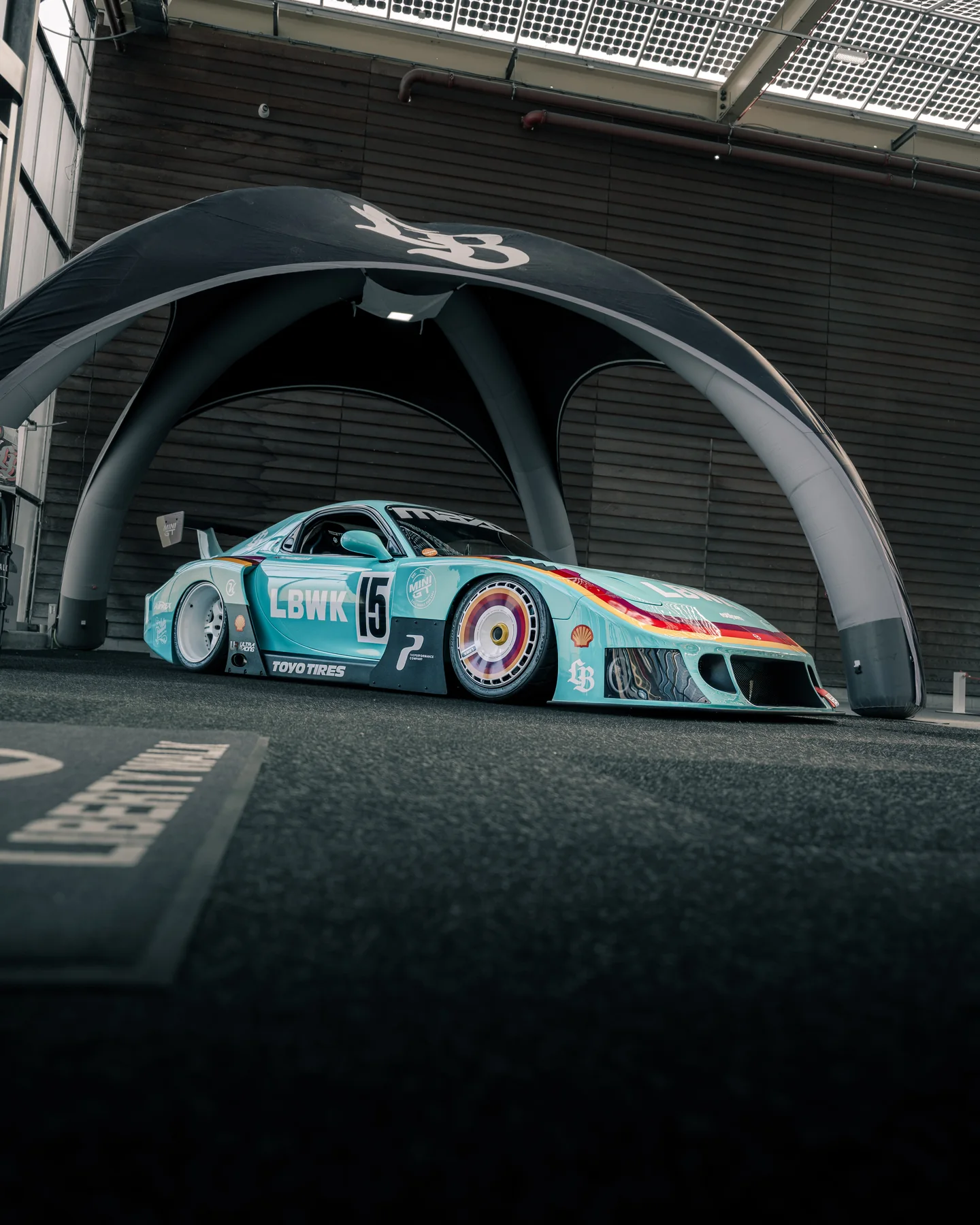 Race car beneath a modern concrete arch