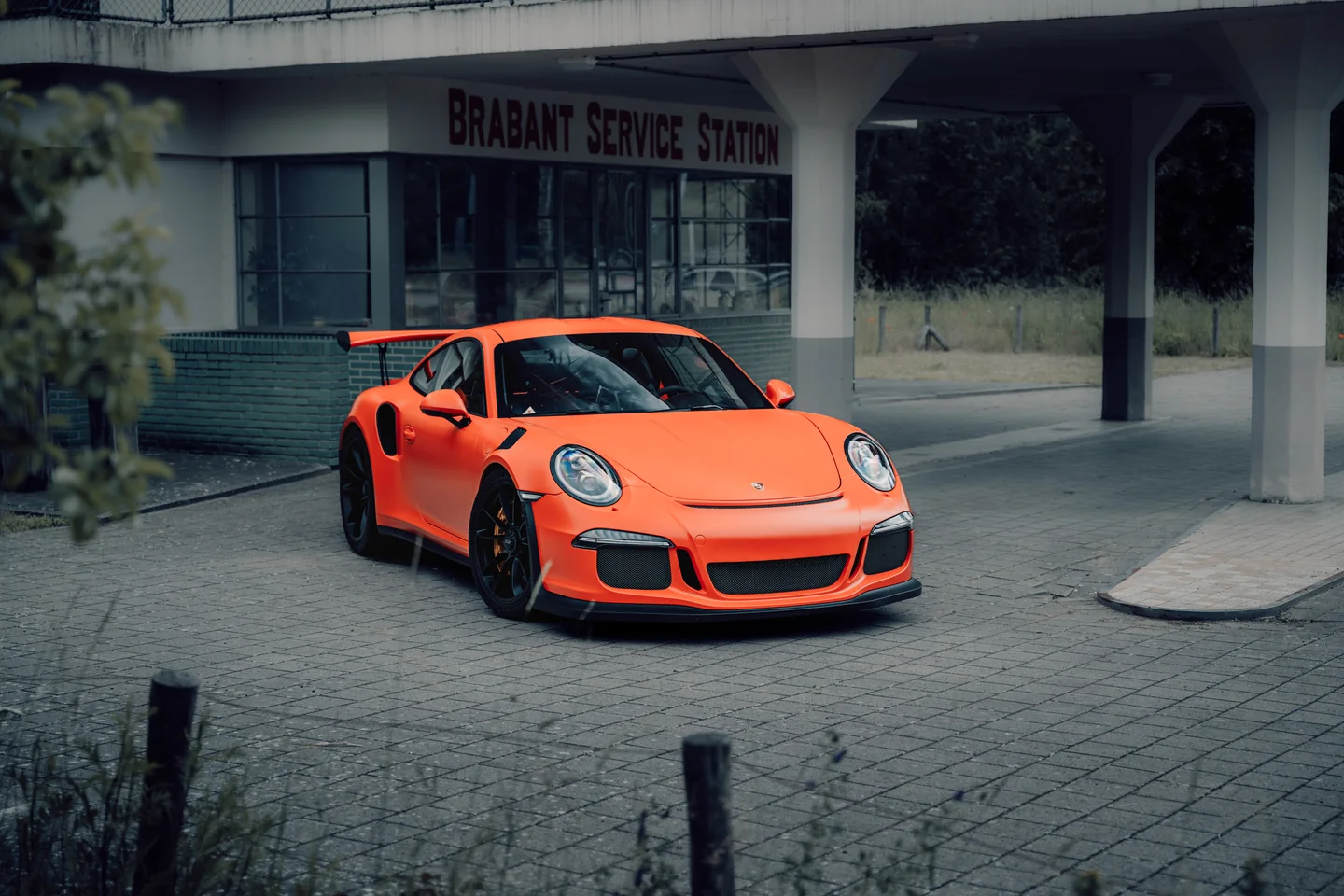 Orange Porsche beside a disused petrol station