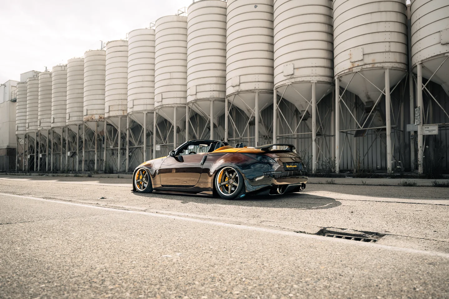 Lowered sports car beside industrial silos