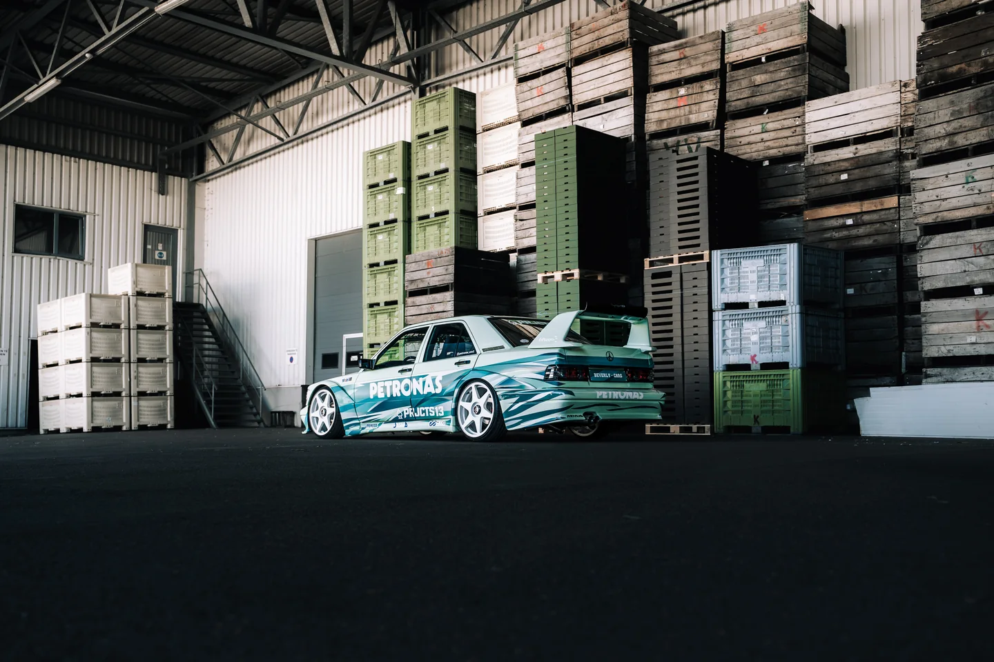 Petronas-liveried Mercedes beside stacked crates