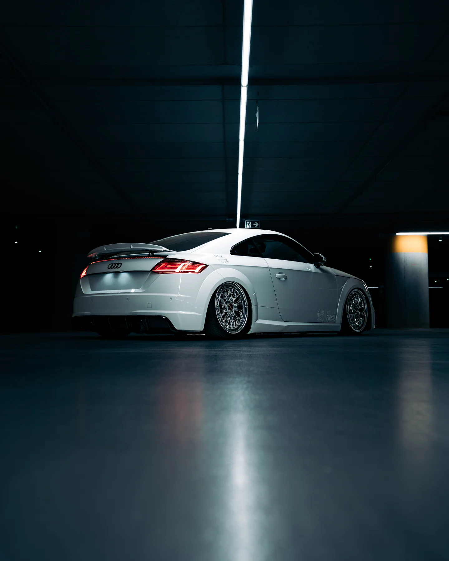 Rear view of a white Audi TT beneath strip lighting